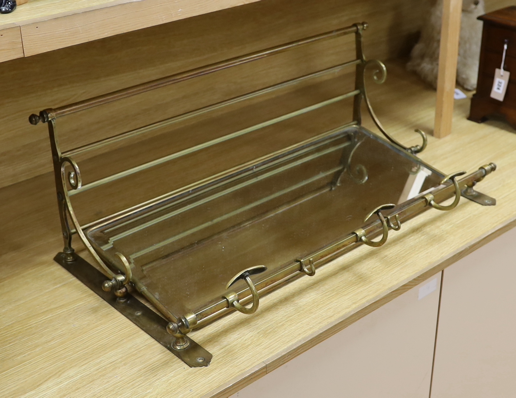 A brass wall hall mirror, with coat hooks and hat shelf, possibly from a train, 80cm wide x 46cm high